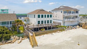 A beachfront property with multiple buildings, including a large house with a deck and a smaller house with a balcony.