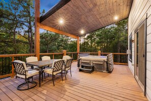 A covered outdoor deck with a hot tub, dining table, and chairs. - Pets, Big Deck, Hot Tub, Fire Pit, Mountainside Escape (Broken Bow)