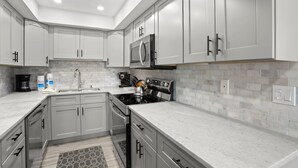 Une cuisine moderne avec des meubles gris, une cuisinière en acier inoxydable et un four à micro-ondes.