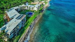 Vista aerea di un hotel sulla costa con piscina, spiaggia privata e rigogliosa vegetazione.