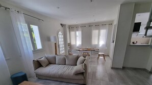 Un'ampia zona giorno con divano, tavolino in legno e zona pranzo con tavolo e sedie.