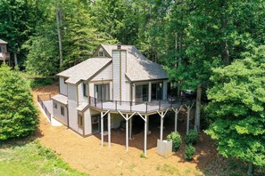 A two-story house with a balcony, surrounded by trees.
