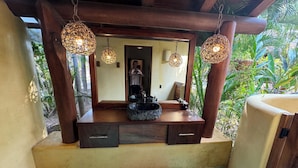 Une salle de bain avec un meuble-lavabo en bois, un grand miroir et deux luminaires suspendus.