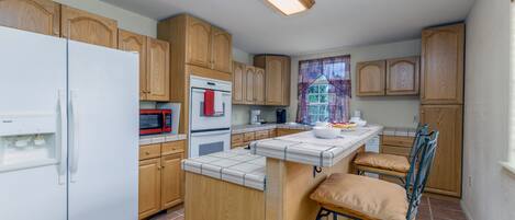 A kitchen with wooden cabinets, a white refrigerator, a microwave, and a sink.