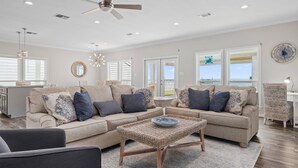 A spacious living room with a large sectional sofa, a coffee table, and a ceiling fan.