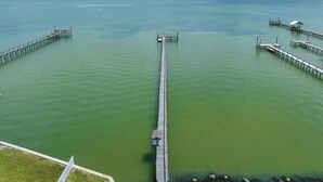 A long pier extending into a calm body of water with a clear sky above. - The Castaway by Miss Kitty’s (Rockport)