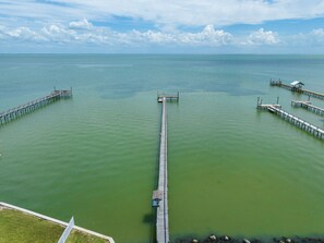 A long pier extending into a calm body of water with a clear sky above. - The Castaway by Miss Kitty’s (Rockport)