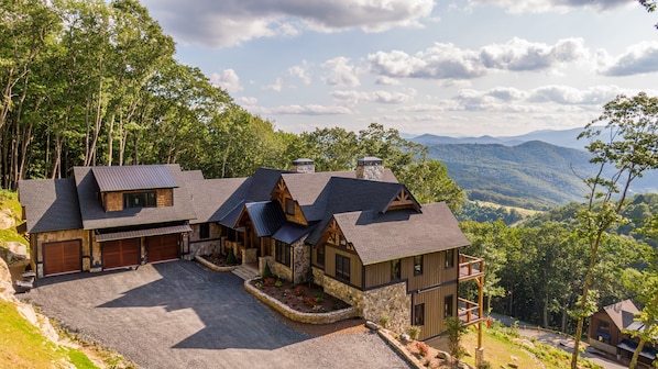 Une cabane comprenant plusieurs pièces, dotée d’une façade en pierre et offrant une vue sur la forêt et les montagnes environnantes.