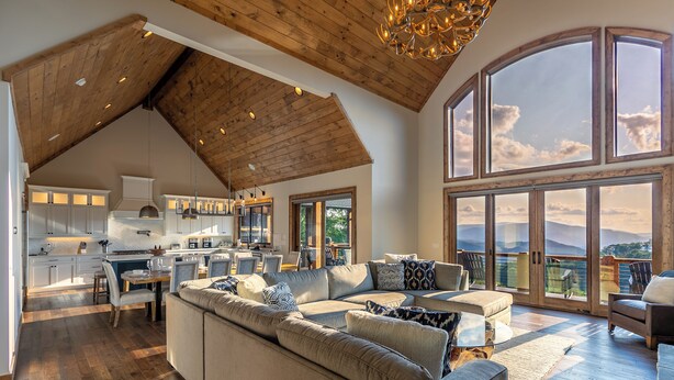 A spacious living area with a large sofa, a dining table, and a kitchen in the background. - Up & Away at Eagles Nest | Luxury Mountain Home | Sleeps 24 | Views + Hot Tub (Banner Elk)