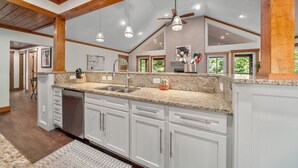 A spacious kitchen with granite countertops, white cabinetry, and a high ceiling with exposed beams. - Mountaintop Ridge | Near Asheville with Pool, Fire Pit, and Ranging Views (Fairview)
