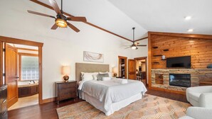 A bedroom with a bed, a TV, a fireplace, and a ceiling fan. - Mountaintop Ridge | Near Asheville with Pool, Fire Pit, and Ranging Views (Fairview)