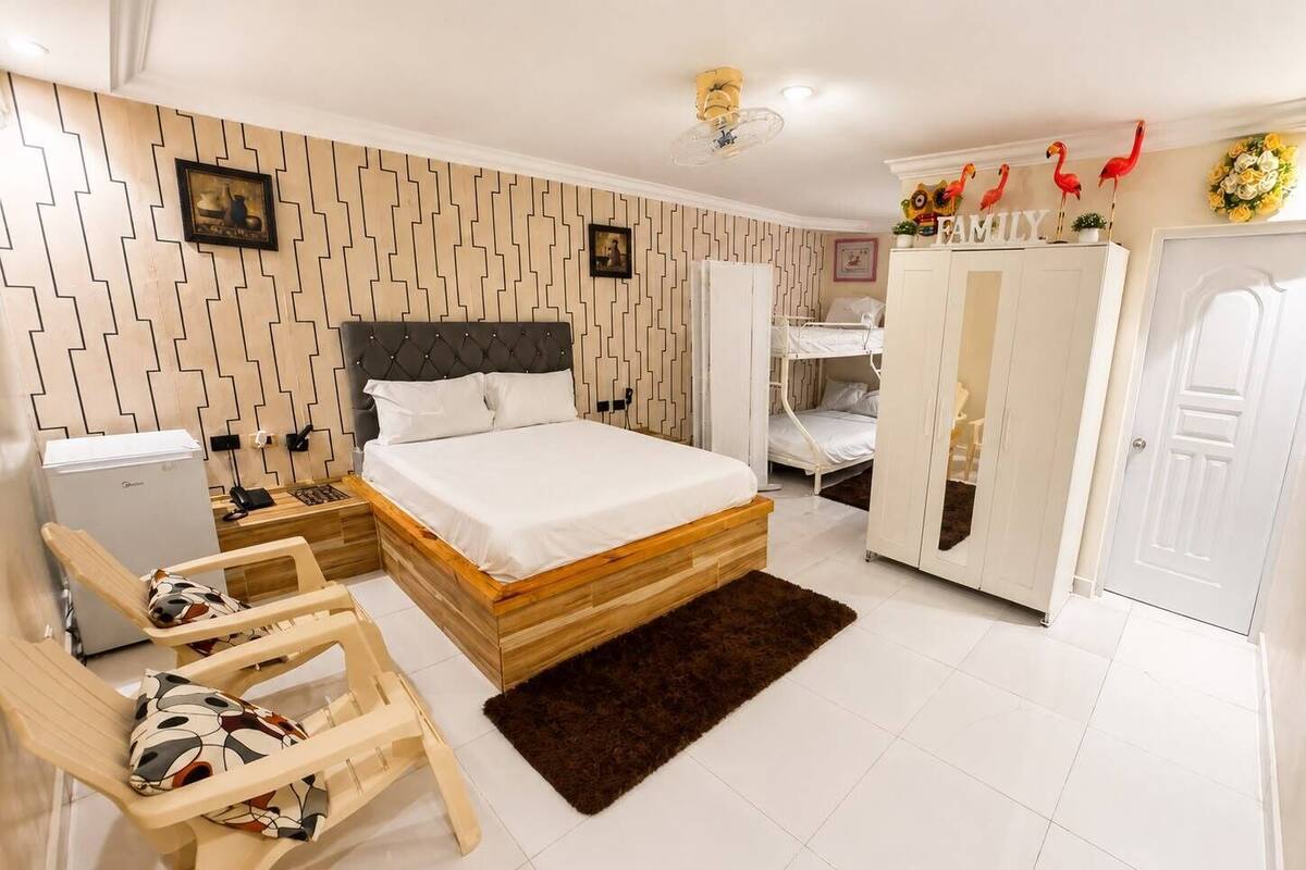 A bedroom with a bed, a desk, a chair, a wardrobe, and a bunk bed.