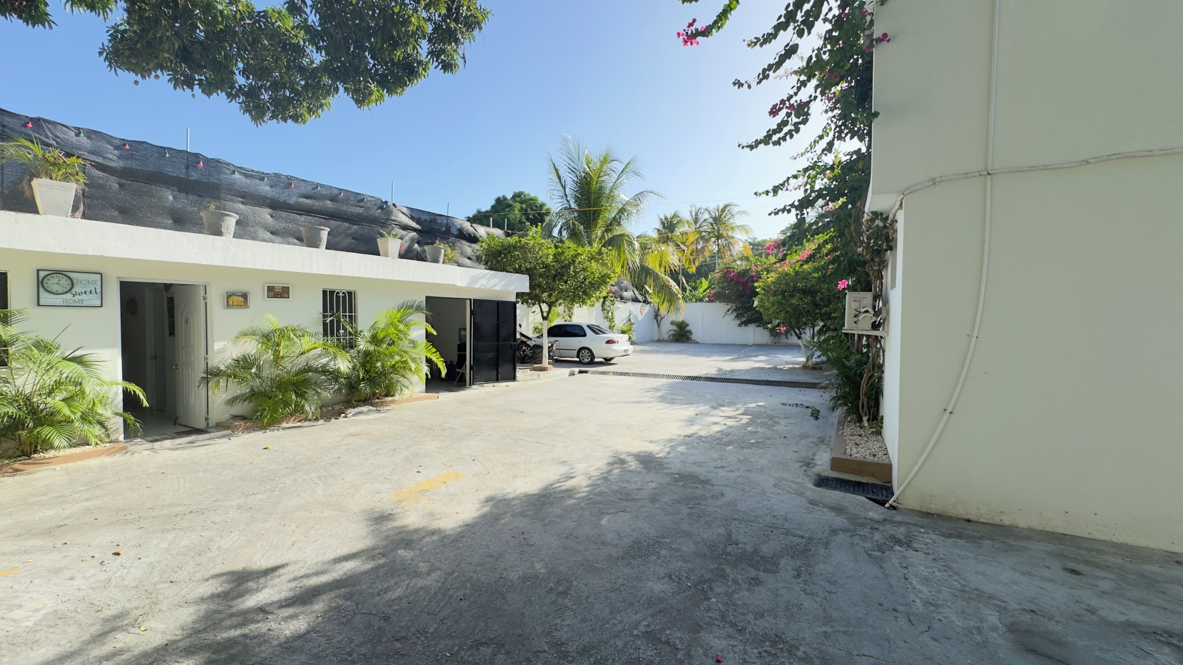 A residential building with a gated entrance, a parked car, and potted plants.