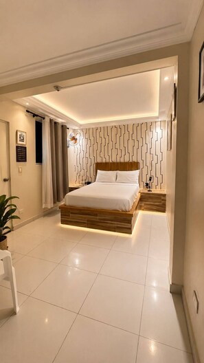 A modern bedroom with a bed, bedside tables, a potted plant, and a wall with a geometric pattern. - Hotel 1325 (Bani)