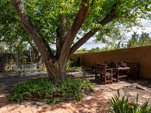 Un espace patio agrémenté d’un grand arbre, de sièges d’extérieur et d’un chemin en briques.