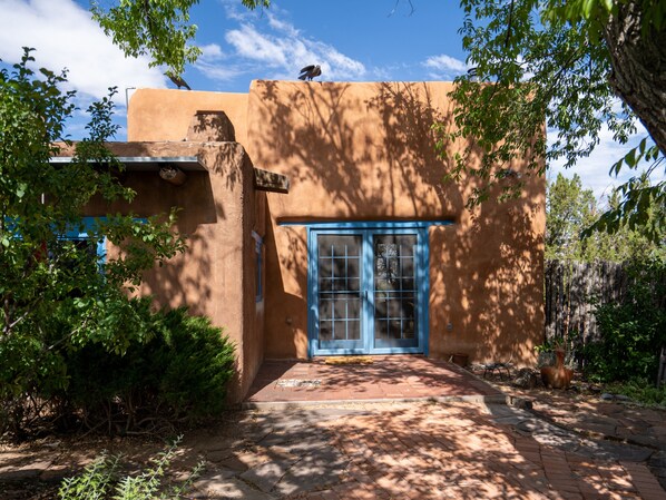 A rustic building with a blue door and a small porch area. - Caster's Retreat by Kokopelli Property Management (Santa Fe)