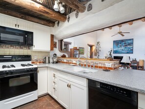 A kitchen with white cabinets, a black stove, a microwave, and a dishwasher. - Caster's Retreat by Kokopelli Property Management (Santa Fe)