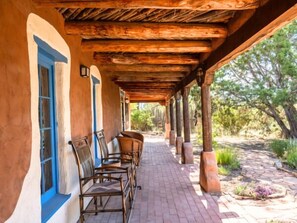 A covered outdoor seating area with wooden chairs and a brick pathway. - Caster's Retreat by Kokopelli Property Management (Santa Fe)