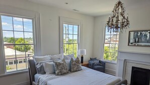 A bedroom with a large bed, a fireplace, and multiple windows.