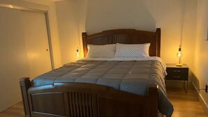 A bedroom with a wooden bed, two bedside tables with lamps, and a door. - Private Lake House (Puyallup)