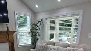 Ein Wohnzimmer mit einem beigen Sofa, gemusterten Kissen, einem Glastisch und einem Teppich mit Sternenmuster.