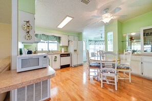 Kitchen area with central island and dining table, featuring a microwave, refrigerator, and dishwasher.