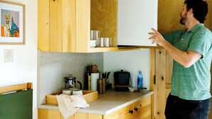A kitchen with wooden cabinets, a countertop, and various kitchen appliances. - The Cabins at Reverence Farms by Sagra (Graham)