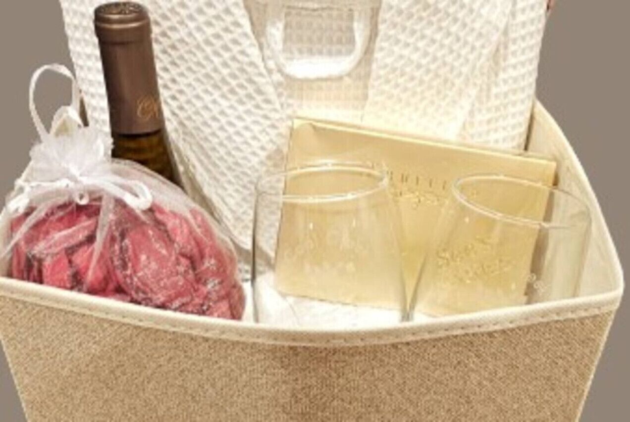 En presentkorg med en flaska, två glas och en inslagen gåva.