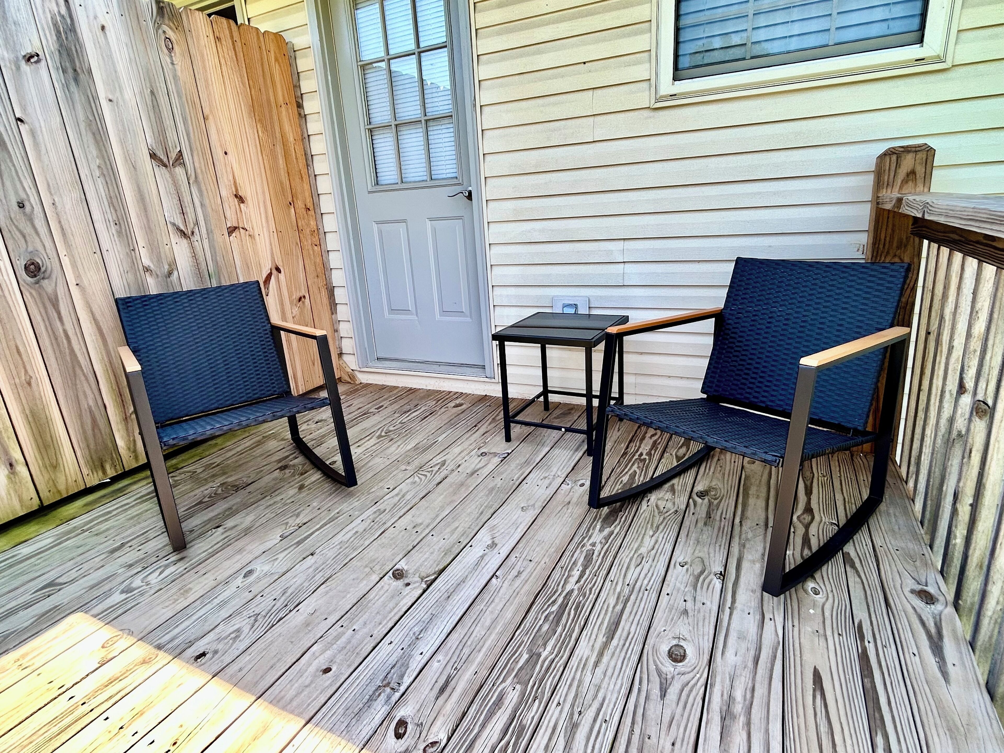 Eine Holzterrasse mit zwei blauen Stühlen und einem kleinen Tisch.