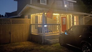 Ein zweistöckiges Haus mit Veranda, Holzzaun und einer amerikanischen Flagge.