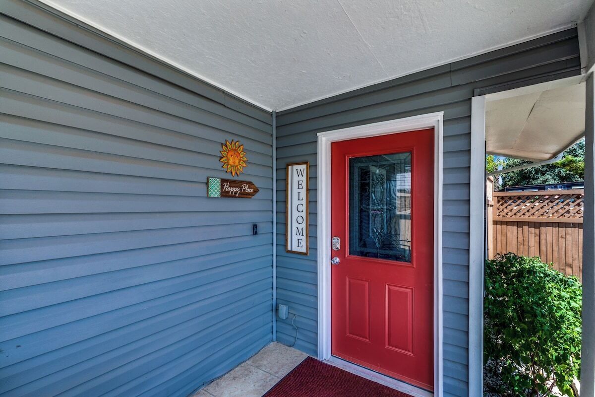 A house with a red door, a 'Welcome' sign, and a 'Happy Place' sign on the wall.