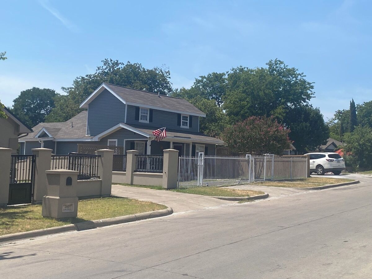 A residential house with a gated driveway, a mailbox, and a flag.