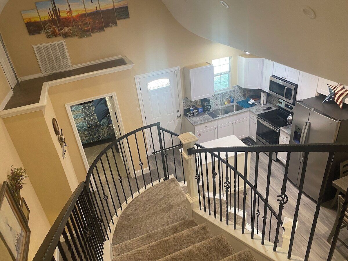 A spacious kitchen with modern appliances, a dining area with a table and chairs, and a staircase with a railing.