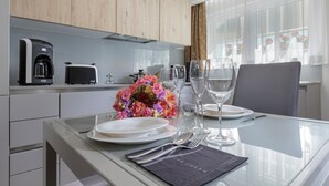 A modern kitchen with a dining area. It includes a coffee maker, toaster, and a vase of flowers on the counter. - Villa Vinicia 1 Deluxe Apartment (Luxembourg)