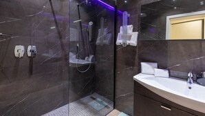 Une salle de bain moderne avec une douche en verre, un grand miroir et un mur recouvert de carreaux de marbre.