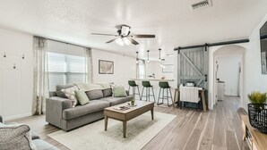 Una sala de estar moderna con un sofá gris, una mesa de centro de madera y un ventilador de techo.