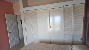 A bedroom with a bed, a wardrobe, and a door. - Apartment, with pool near Jan Thiel Beach! 
 (Willemstad)