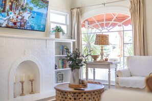 A living room with a fireplace, bookshelves, a television, and a view of the outdoors.