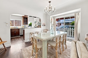 A spacious kitchen with a dining area, a chandelier, and a view through large windows. - Bay front beach home, steps to the sand, shopping & dining. Parking, AC - clean! (Long Beach)
