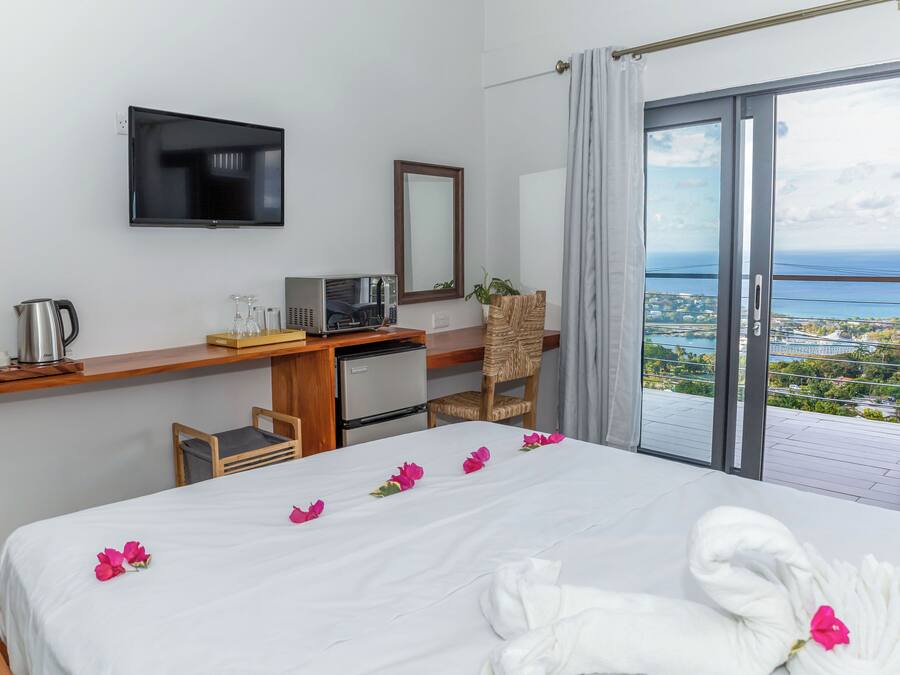 Ein Hotelzimmer mit Bett, Schreibtisch mit Computer, Fernseher und Balkon mit Blick.