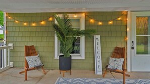 A porch with two wooden chairs, a potted plant, and a 'WELCOME' sign. - Cozy Lake Retreat (Honeoye)