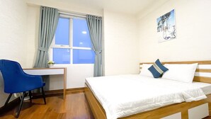 Un dormitorio con cama, escritorio, silla y ventana con cortinas.