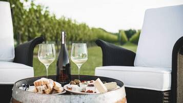 A dining setup with a wine bottle, glasses, and a plate of cheese and crackers on a barrel.
