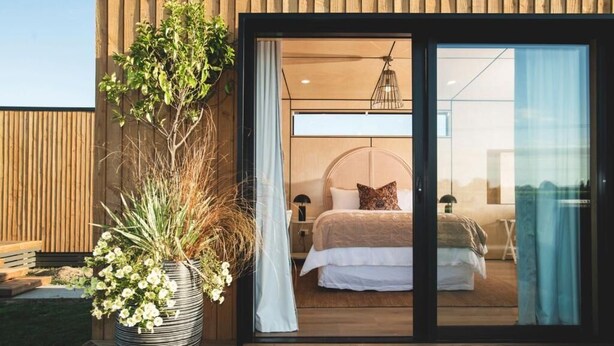 A modern bedroom with a large bed, a nightstand, and a potted plant. - Matawhero Wines  (Gisborne)