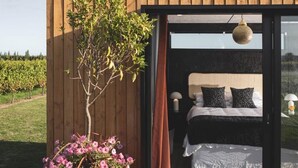 A bedroom with a bed, pillows, and a bedside table. - Matawhero Wines  (Gisborne)