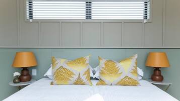 A hotel room with a bed, two bedside lamps, and a window with blinds.