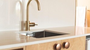 A modern kitchen with a gold faucet, a built-in sink, and wooden cabinets. - Matawhero Wines  (Gisborne)