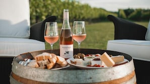 A table with a bottle of wine, two glasses, and a variety of cheeses and bread. - Matawhero Wines  (Gisborne)