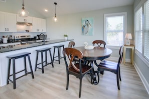 Una cocina moderna con armarios blancos, una isla central y taburetes de bar.