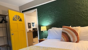 A room with a bed, a yellow door, a green wall, and a desk with a lamp. - “The Clementine” Boho Home in Orlando’s Food Scene (Orlando)